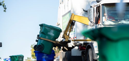 City refuse collection vehicle emptying a green bin